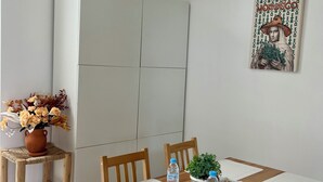 Een eetgedeelte met een houten tafel, stoelen, een bloevas en een waterfles.