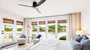 A spacious bedroom with a large bed, a ceiling fan, and a view of a lake.