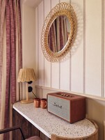 A bathroom with a round mirror, a radio, a lamp, and a towel rack.