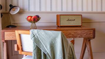 Un escritorio de madera con un altavoz Marshall antiguo, un espejo y un bol de manzanas.