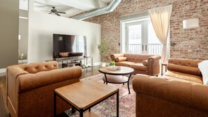 Un salon avec un mur en briques, une cheminée et une grande fenêtre avec des rideaux.