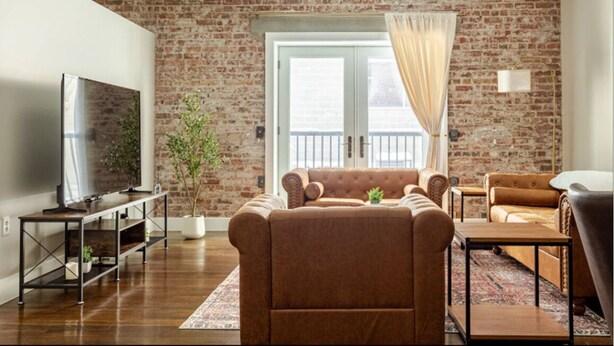 Un salon avec un mur en briques, un canapé, un téléviseur et une plante en pot.