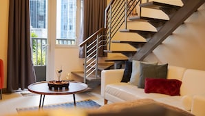 A modern living room with a white sofa, a round coffee table, and a staircase with a metal railing.