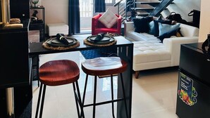 A modern living space with a staircase, a dining area with stools, and a sofa.