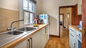 Een kleine keuken met een dubbele spoelbak, een koelkast en een houten aanrecht.