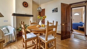 Een eetgedeelte met een houten tafel, stoelen en een vaas met zonnebloemen.