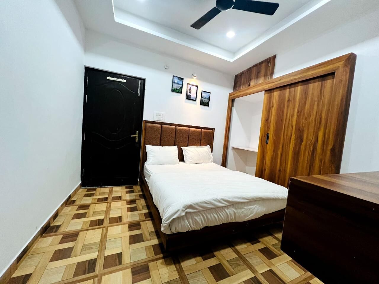 A bedroom with a bed, a ceiling fan, a wardrobe, and a wooden floor.