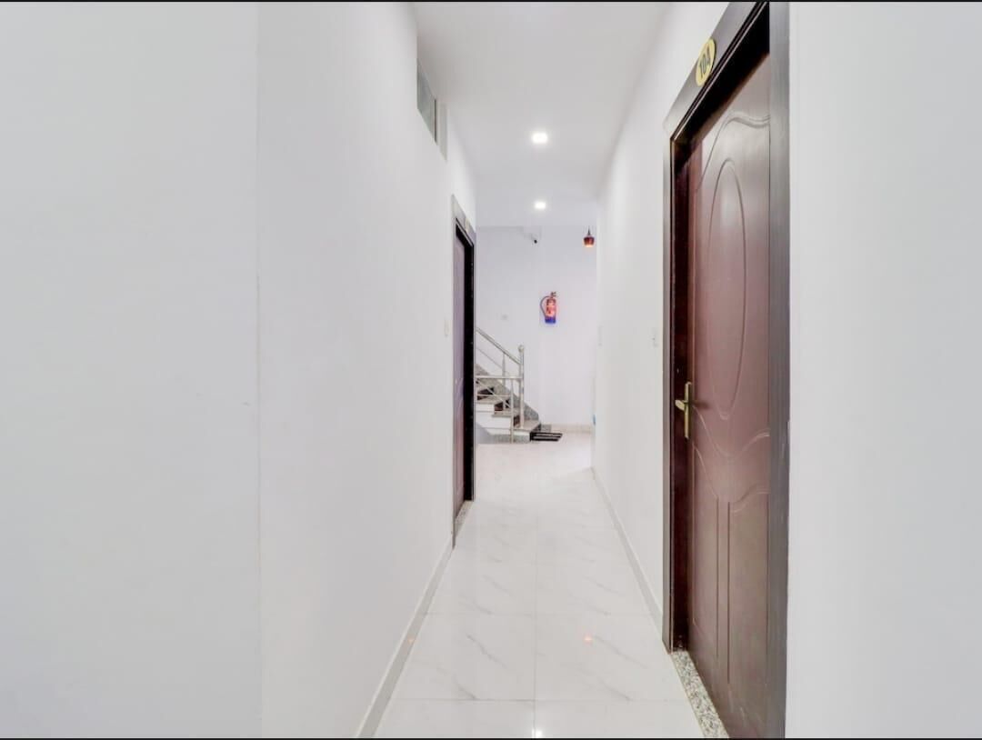 A corridor with a marble floor leading to a staircase and a closed door.