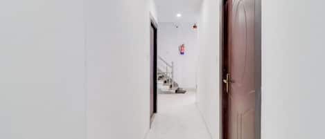 A corridor with a marble floor leading to a staircase and a closed door.