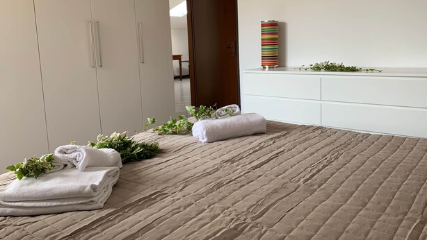 A hotel room with a bed, a wardrobe, a bedside table with a decorative vase, and an air conditioning unit. - Casa Piera-Comfortable apartment in San Pietro in Cariano, Casa Piera - Comodo appartamento a San Pi... (San Pietro In Cariano)