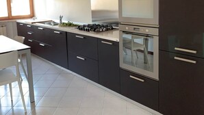 A modern kitchen with dark cabinets, stainless steel appliances, and a white countertop. - Casa Piera-Comfortable apartment in San Pietro in Cariano, Casa Piera - Comodo appartamento a San Pi... (San Pietro In Cariano)