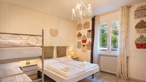 Ein Schlafzimmer mit Etagenbetten, einem Kronleuchter, einem fenster mit Vorhängen und Wanddekorationen.