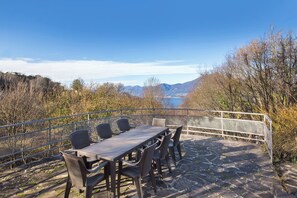 An outdoor dining area with a table and chairs, overlooking a scenic landscape with mountains and a body of water. - Villa Elisabetta - Quiet with lake view, Villa Elisabetta - Tranquilla con vista lago (San Zeno di Montagna)
