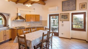 A kitchen with wooden cabinets, a gas stove, and a dining area with a table and chairs.