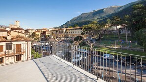 Un balcon donnant sur un parking, des immeubles et des montagnes.