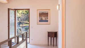 Un couloir avec un plafond en bois, un tableau accroché au mur, une petite table et une porte.