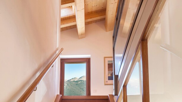 Un escalier en bois offrant une vue sur un paysage montagneux, visible à travers une porte située en haut.