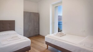 A bedroom with two beds, a wardrobe, and a balcony with a view of the sea. - Casa Sofia - Lake view, Casa Sofia - Casa vista lago (Pai)