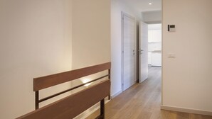 A hallway with a wooden bench, a white door, and a view into a kitchen area. - Casa Sofia - Lake view, Casa Sofia - Casa vista lago (Pai)