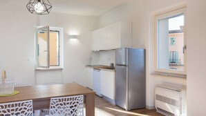 A modern kitchen with white cabinets, a stainless steel refrigerator, and a window with a view of buildings. - Casa Sofia - Lake view, Casa Sofia - Casa vista lago (Pai)