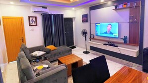 A modern living room with a sofa, a dining table, and a TV.