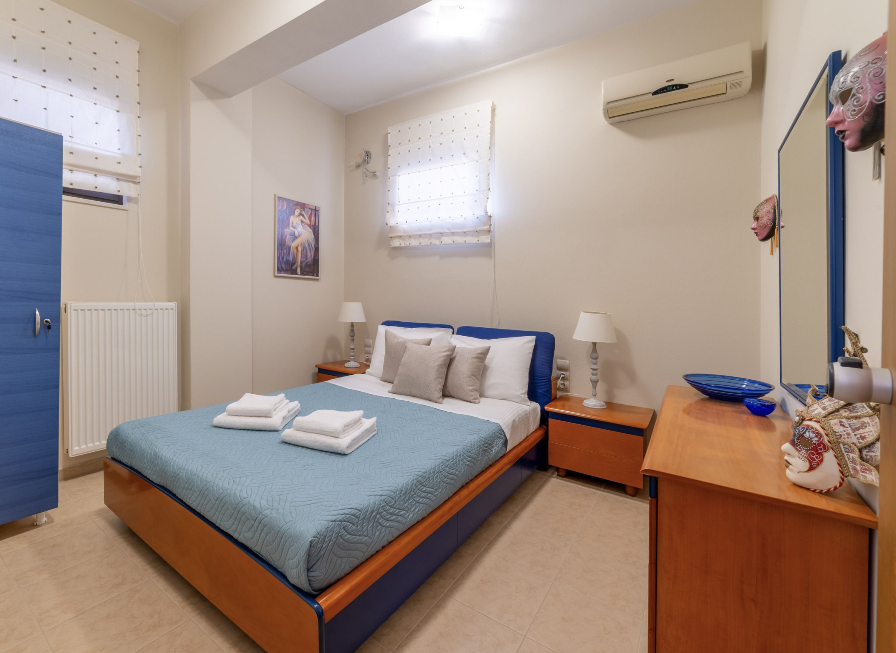 A bedroom with a bed, two bedside tables, a dresser, a mirror, and a window with curtains.