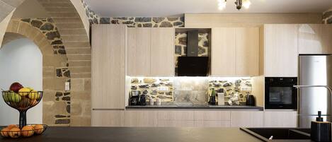 Una cocina moderna con un arco de piedra, armarios de madera, horno empotrado y refrigerador de acero inoxidable.