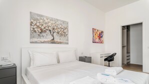 Una habitación de hotel moderna con una cama grande, un escritorio y un vestidor.