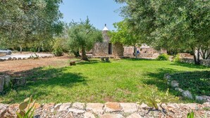 A courtyard with a stone building, surrounded by trees and a grassy area. - Casa di Paolo - Lamia by Rentbeat (Ceglie Messapica)
