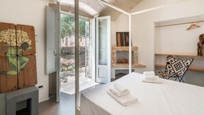 A room with a bed, a wooden artwork, a fireplace, and a view of the outside. - Casa di Paolo - Lamia by Rentbeat (Ceglie Messapica)