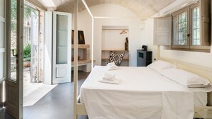 A bedroom with a bed, a wardrobe, a mirror, and a door leading outside. - Casa di Paolo - Lamia by Rentbeat (Ceglie Messapica)