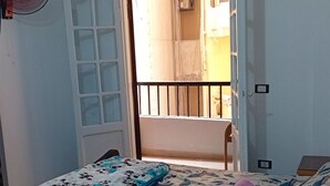 A bedroom with a bed, a window with a view of the outside, and a door leading to another room. - Furnished apartment for rent in miamiAlexandria (Alexandria Governorate)