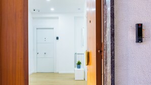 A hotel lobby with a wooden floor, a white door, and a wall-mounted control panel. - Carlo III guest house (Naples)