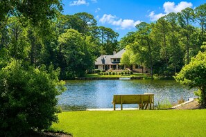 A lakeside property with a house, a dock, and a bench.