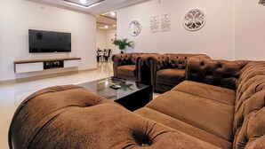 A modern living room with a sectional sofa, a flat-screen TV, and a ceiling fan.