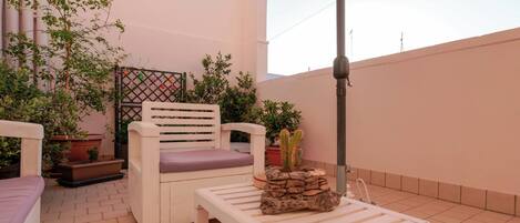 A patio with a white chair, a small table, and potted plants.