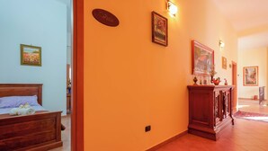 Une chambre d’hôtel avec un lit en bois, un petit bureau, une lampe fixée au mur et un tableau encadré.