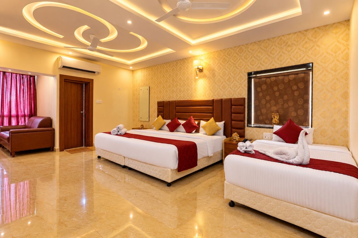 A hotel room with two beds, a sitting area, and a decorative ceiling.