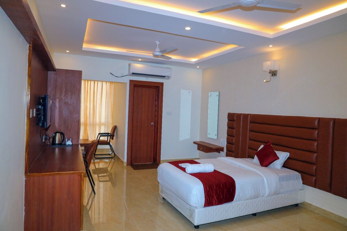 Ein Hotelzimmer mit Bett, Schreibtisch, Stuhl, Deckenventilator und Klimaanlage.