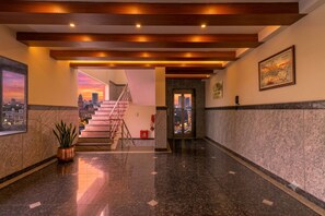 A hotel lobby with a staircase leading to an upper floor, a fire extinguisher, and a framed map on the wall. - Hotel Lorven (Tirupati)