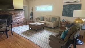 Una sala de estar con chimenea, un sofá, una mesa de centro, un televisor y un mapa en la pared.