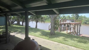 Un espacio al aire libre techado con una parrilla, una terraza de madera y vista a un lago.