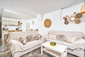 A living room with two sofas, a coffee table, and a kitchen in the background. - Apartment 'Lily' with Sea View, Wi-Fi and Air Conditioning (Almuñécar)