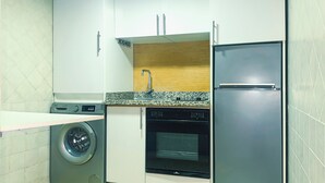 A compact kitchen with a washing machine, dishwasher, and refrigerator.