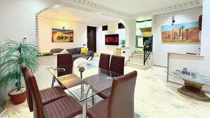 A modern living room with a dining area, a staircase, and a painting on the wall.