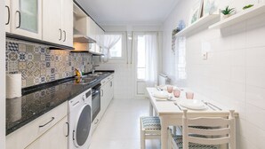 Et moderne køkken med mønstrede fliser, en vaskemaskine og et spiseområde med et bord dækket til to personer.