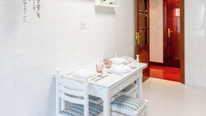 Et hvidt badeværelse med et hvidt toiletbord, en hængende plante og en hylde med pynteting.