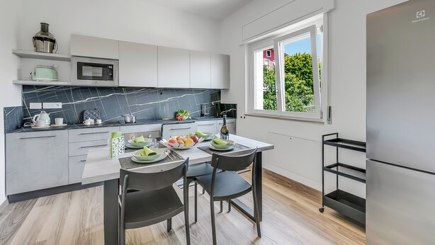 A modern kitchen with white cabinets, a marble backsplash, and a large window. - Casa Tramonti: Mountain-view With Terrace Dining (Gemonio)