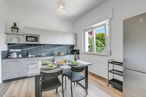Eine moderne Küche mit weißen Schränken, einer Marmor-Spritzschutzleiste und einem Essbereich mit Tisch und Stühlen.