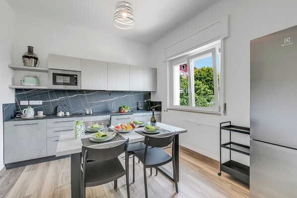 A modern kitchen with white cabinets, a marble backsplash, and a large window. - Casa Tramonti: Mountain-view With Terrace Dining (Gemonio)